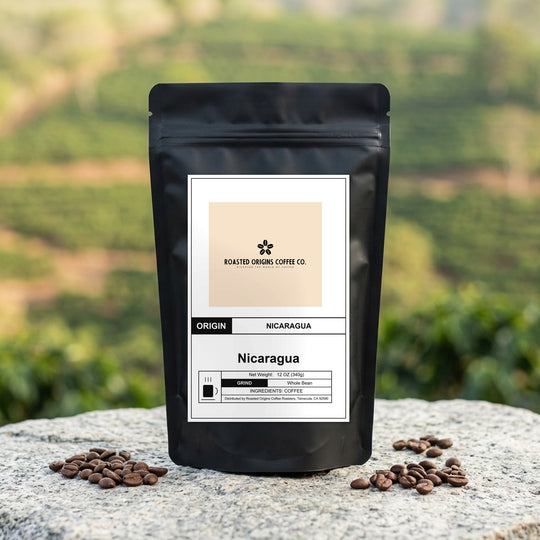 Nicaragua coffee bag standing on pale granite outdoors, roasted beans scattered at its base