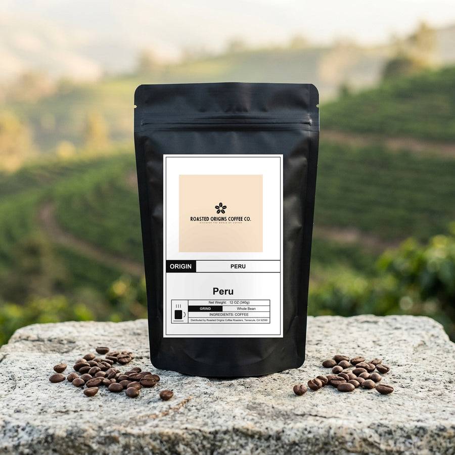 Peru coffee bag standing on pale granite outdoors, roasted beans scattered at its base