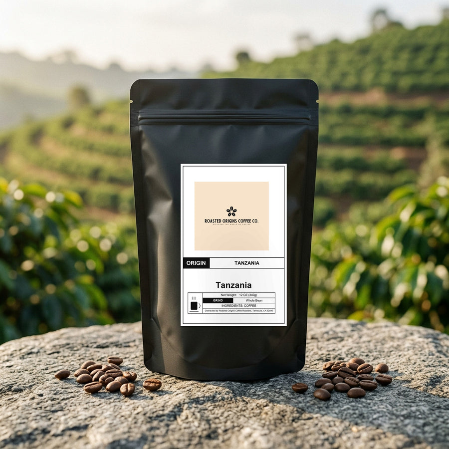 Tanzania coffee bag standing on pale granite outdoors, roasted beans scattered at its base